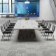 Set of stackable conference chairs with mesh backrest around a large meeting table, ideal for office gatherings.