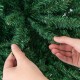Close-up of hands adjusting branch tips on a 7.5 feet artificial Christmas tree made of fireproof PVC material.