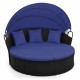 Round wicker patio daybed with retractable blue canopy and cushions, perfect for outdoor relaxation.