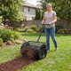 Compost spreader with height-adjustable T-handle, efficiently spreading peat moss in a garden setting.