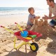 Kids wheelbarrow in red with all-terrain wheels, perfect for hauling toys and sand at the beach for outdoor fun.