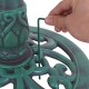 Hand inserting a ground stake into the base of a green pedestal bird bath feeder for added stability outdoors.