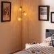 Three-globe floor lamp with golden finish, acrylic shades, foot switch, ideal for home or cafe lighting.