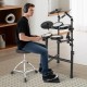 Electric drum set with double-layer mesh pads, adjustable stool, and headphones for silent practice in a modern setting.