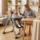 Foldable high chair in gray with detachable cushion, adjustable height, and safety harness for babies and toddlers.