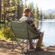 Oversized green camping chair with side pockets and cup holder, perfect for outdoor relaxation by the water.