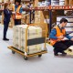 Folding platform cart dolly with black vinyl platform, 660lbs capacity, shown in a warehouse setting with boxes.