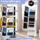 LED lights illuminate the inside of the freestanding white jewelry armoire, showcasing dual mirrors and organized.