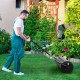Metal lawn roller with detachable gripping handle, 17-gallon capacity, used for leveling grass in a garden.
