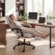 Ergonomic gray gaming chair with headrest, reclining backrest, and retractable footrest for optimal comfort in office.
