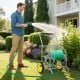 Garden hose reel cart with 2 wheels, storage basket, and foam-padded handrail for easy maneuvering in the garden.