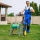 Garden hose reel cart with two wheels, storage basket, and foam-padded handrail for easy maneuvering in the yard.
