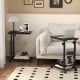 C-shaped rolling side table with black finish, featuring height adjustability and wheels for easy movement beside a.