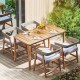 Outdoor acacia wood dining set with four gray wicker chairs and cushions, perfect for backyard or patio dining.