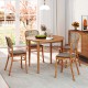 Round 36-inch acacia wood outdoor dining table for 4 with slatted design, placed in a bright indoor setting.