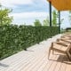 Artificial lily leaf privacy fence displayed on a wooden deck, providing a decorative backdrop for outdoor spaces.