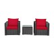 Two patio chairs with red cushions and a glass-top table, made of durable rattan for outdoor relaxation.