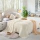 Beige double-sided throw blanket featuring shaggy fur and smooth velvet, perfect for cozying up on a bed or sofa.