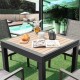 Extendable patio table with a wood-like slatted top, accommodating 4-6 people, shown in a stylish outdoor setting.
