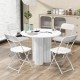 Four white metal folding chairs with plastic seats arranged around a round table, ideal for home and office use.
