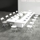 White metal folding chairs arranged around a large conference table, ideal for office meetings and events.