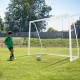 Youth soccer player kicking a ball towards an 8 x 6 ft weather-resistant soccer goal with ground stakes and cones.