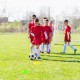 Youth soccer players practice with a ball and cones near a weather-resistant 8 x 6 Ft soccer goal on a sunny field.