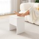 White vanity stool with cushioned seat and hidden storage, perfect as a foot stool or side table in small spaces.