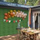 Artificial boxwood wall panels with vibrant balloons and decorations, perfect for outdoor parties and events.