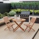 Teak wood folding chairs with slatted design and X-shaped structure, ideal for elegant outdoor dining in the backyard.