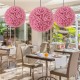 Three 17.5-inch faux pink eucalyptus decorative balls hanging in a bright dining area, perfect for indoor or outdoor.