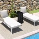 C-shaped end table in black with adjustable foot pads, ideal for indoor or outdoor use, shown beside lounge chairs.