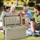 Portable 50 QT tan cooler with integrated cup holders, perfect for outdoor gatherings and keeping drinks cold.