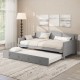 Twin size gray daybed with trundle showcasing integrated armrests and a curved backrest, perfect for guest rooms or.