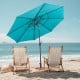 10 ft vented patio umbrella in green with push button tilt, providing shade for two beach chairs by the ocean.