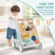 Wooden baby walker activity center in green with wheels, featuring a mirror, xylophone, and shape sorters for toddlers.