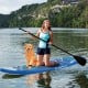 Inflatable stand-up paddle board with a non-slip EVA pad, adjustable paddle, and a dog, perfect for water activities.