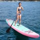 Inflatable stand-up paddle board in pink and teal with a rider, featuring a 3-fin setup for stability on water.
