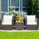 Two wicker patio chairs with white cushions and a glass-top table, perfect for outdoor relaxation in the garden.