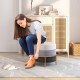 Round upholstered ottoman in gray with gold metal legs, serving as a footrest and vanity stool for versatile use.