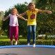 Two children jumping on a trampoline with a blue safety pad, designed for durability and edge-to-edge protection.