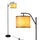 Standing floor lamp with adjustable head, matte black iron frame, and beige fabric shade for living room or bedroom use.