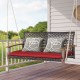 Rattan hanging porch swing chair with red cushion and acacia wood armrests, perfect for outdoor relaxation for two.