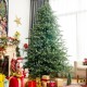 8 feet hinged artificial Christmas spruce tree with mixed PE and PVC tips, set up in a cozy living room for holiday.
