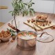 Stainless steel saucepan from the 11-piece cookware set with rose golden handle, filled with colorful stew on a wooden.