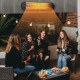Group of friends enjoying warmth from a wall-mounted infrared heater with remote control during an outdoor gathering.