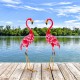Two pink metal flamingo garden statues with U-shaped stakes, perfect for charming backyard or lakeside decoration.