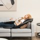 Massage chair pad in black with a woman relaxing, featuring heat and vibration for targeted back relief on a sofa.