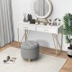 Gray upholstered round ottoman with solid rubber feet, offering storage and comfort for versatile use in any space.