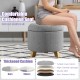 Round gray upholstered ottoman with cushioned seat, solid rubber feet, and storage space for versatile use.